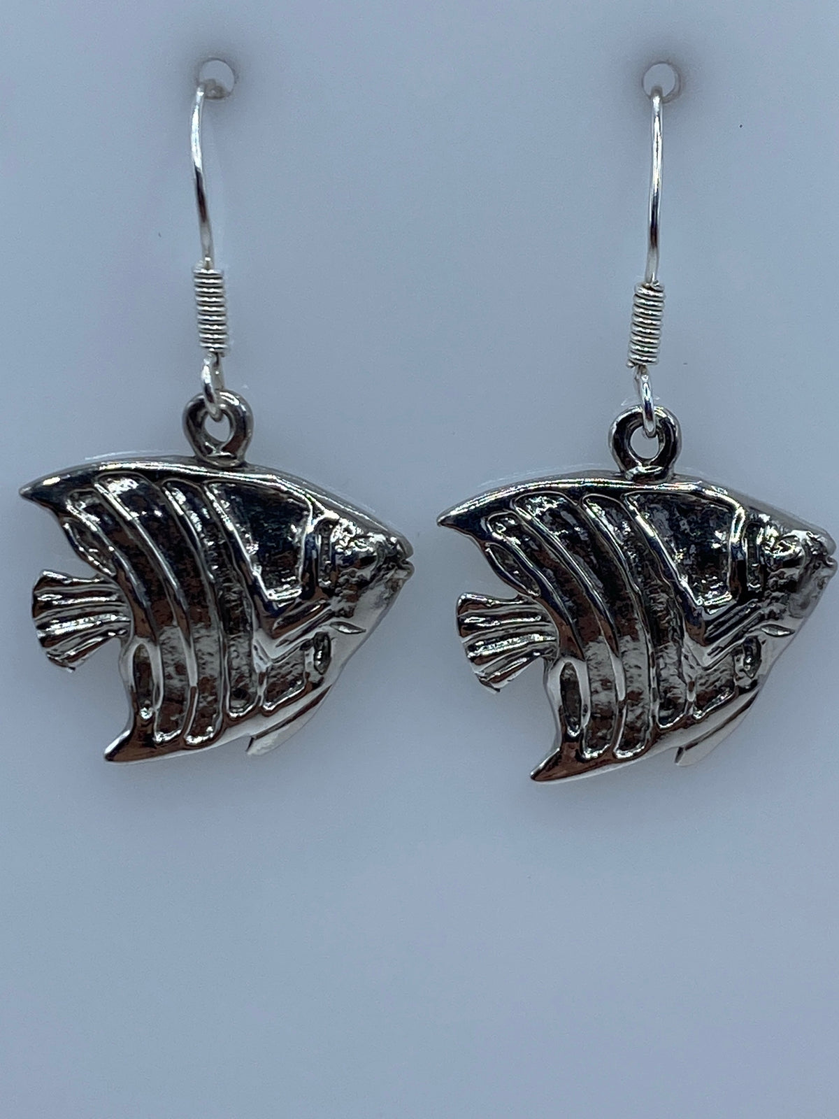 Los dos aretes juntos sobre fondo azul, mostrando el trabajo de repujado artesanal