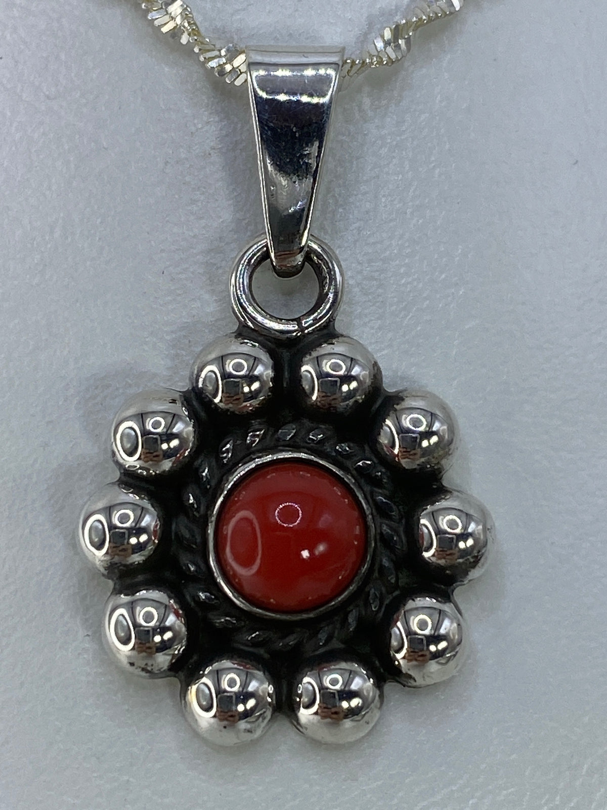 Detalle del engaste a mano del coral rojo en plata pulida
