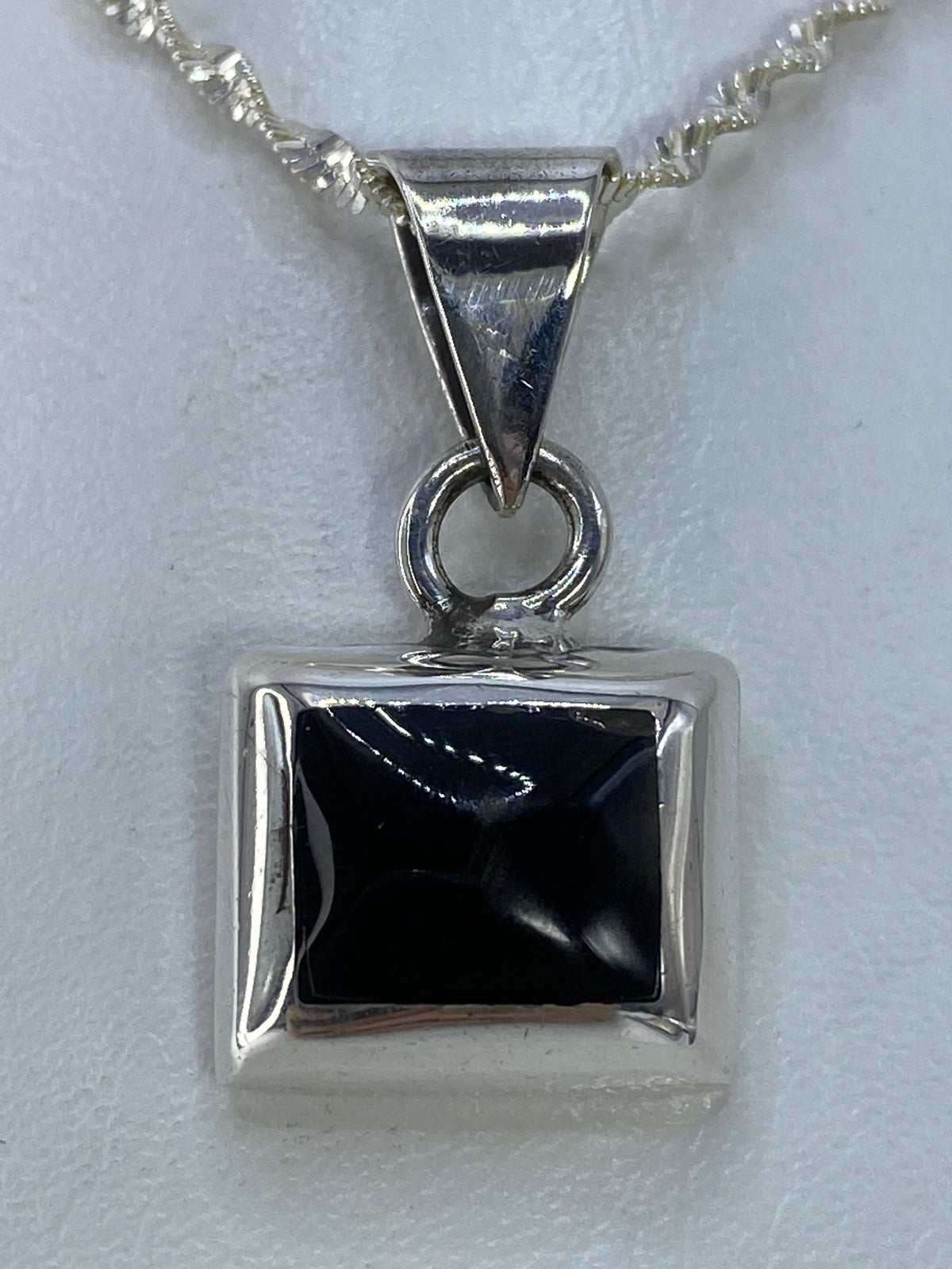 Detalle frontal del dije de ónix negro en marco de plata pulida