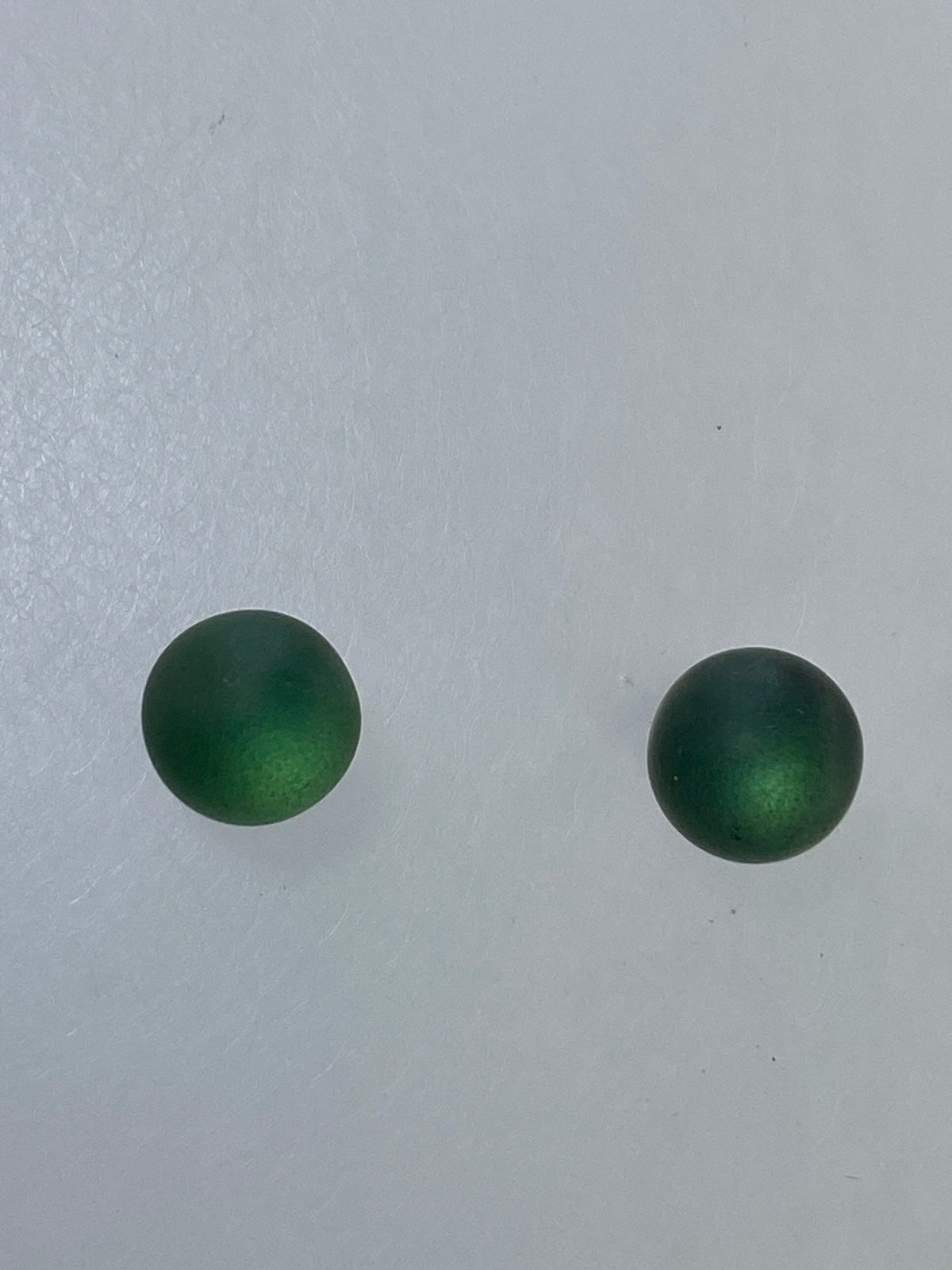 Par de aretes de plata 925 con piedra verde engastada, esfera pulida sobre fondo blanco