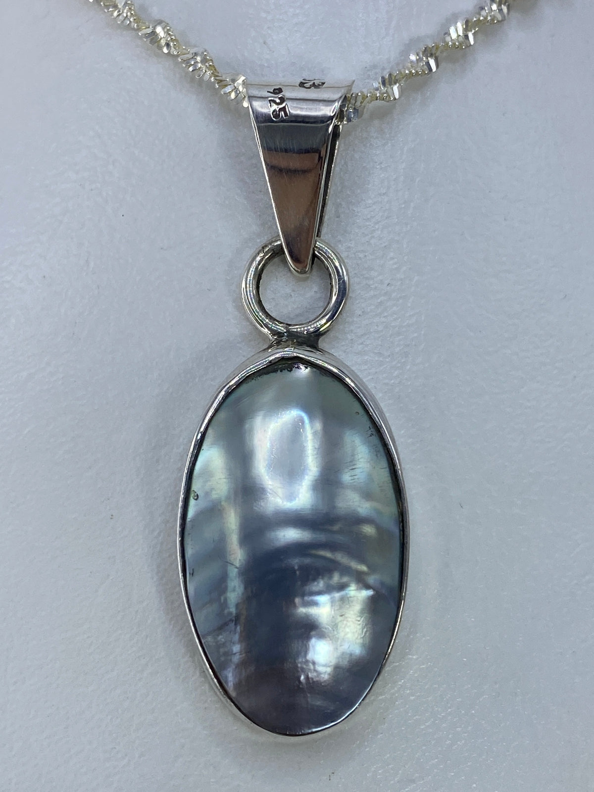 Detalle del engaste a mano en plata y la piedra pulida del dije