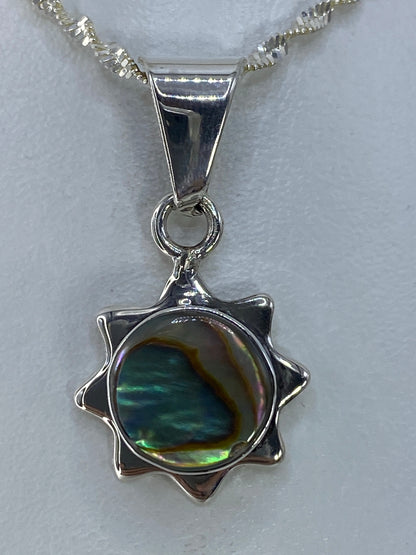 Dije de plata en forma de estrella de 8 puntas con piedra multicolor que refleja verdes, azules y amarillos