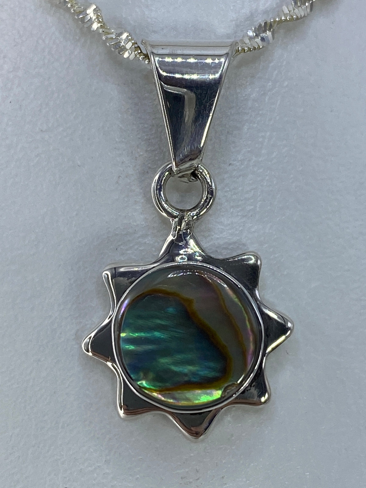 Vista frontal del dije de plata 925 con engaste a mano de piedra multicolor, sobre cadena plateada