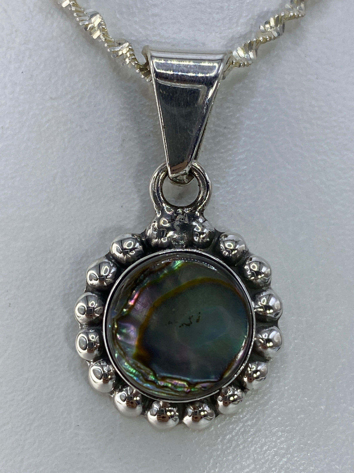 Dije de plata 925 con incrustación multicolor de piedra, en forma floral con perla de Abulón