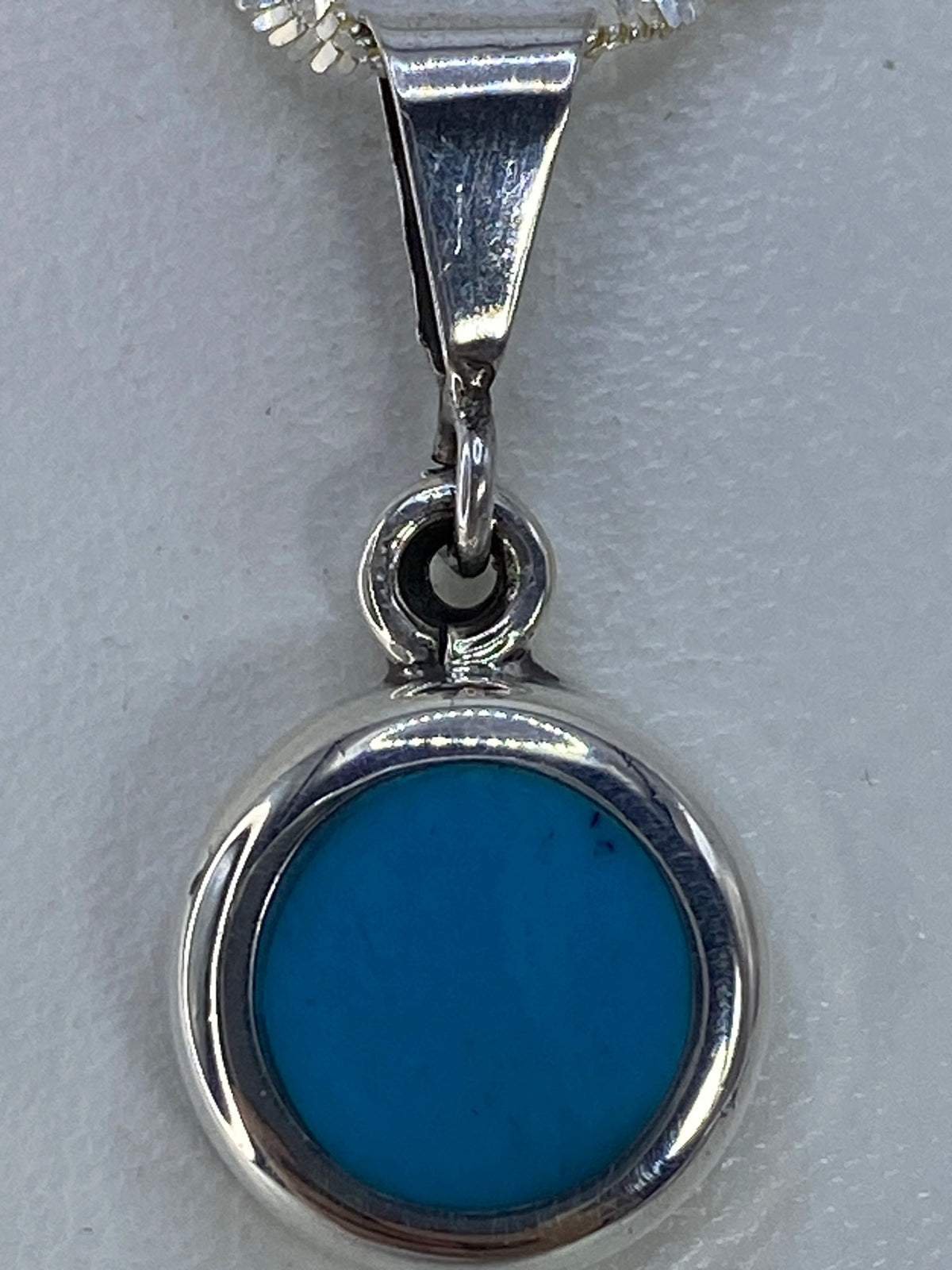 Detalle de la turquesa azul cielo engastada a mano en el dije circular