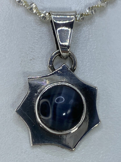 Dije Ojo de Gato negro en plata 925 colgando de cadena sobre fondo blanco