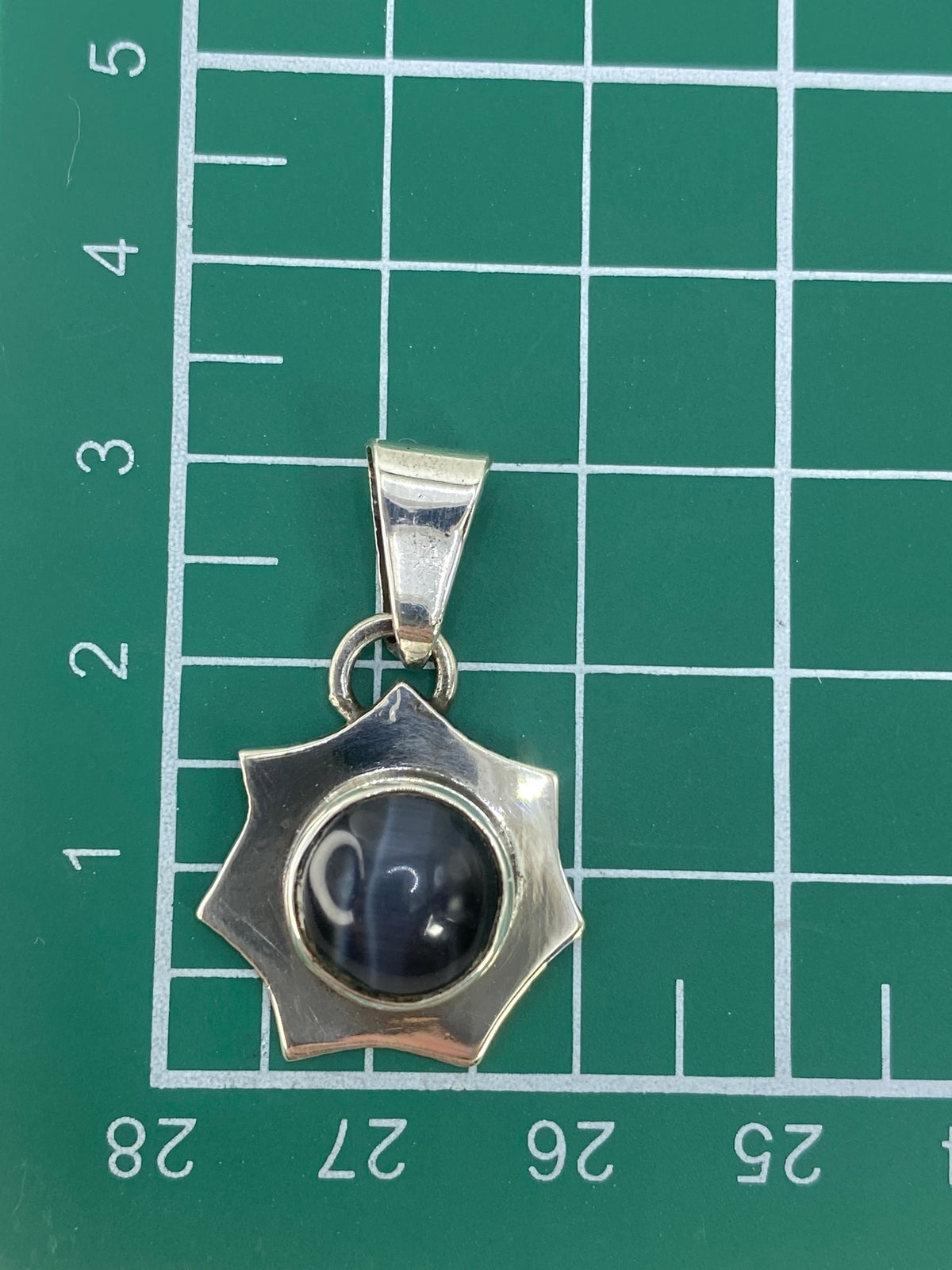 Dije sobre regla mostrando 3 cm de largo y marca 925 en la base