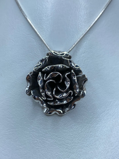 Dije flor de plata 925 con pétalos en relieve colgando de cadena plateada