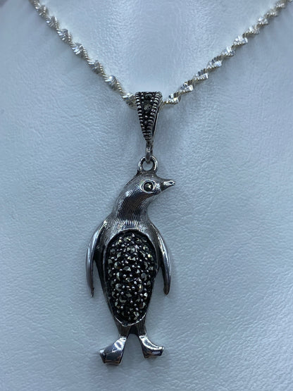 Dije de pingüino de plata 925 con marcasita incrustada, colgando de una cadena plateada