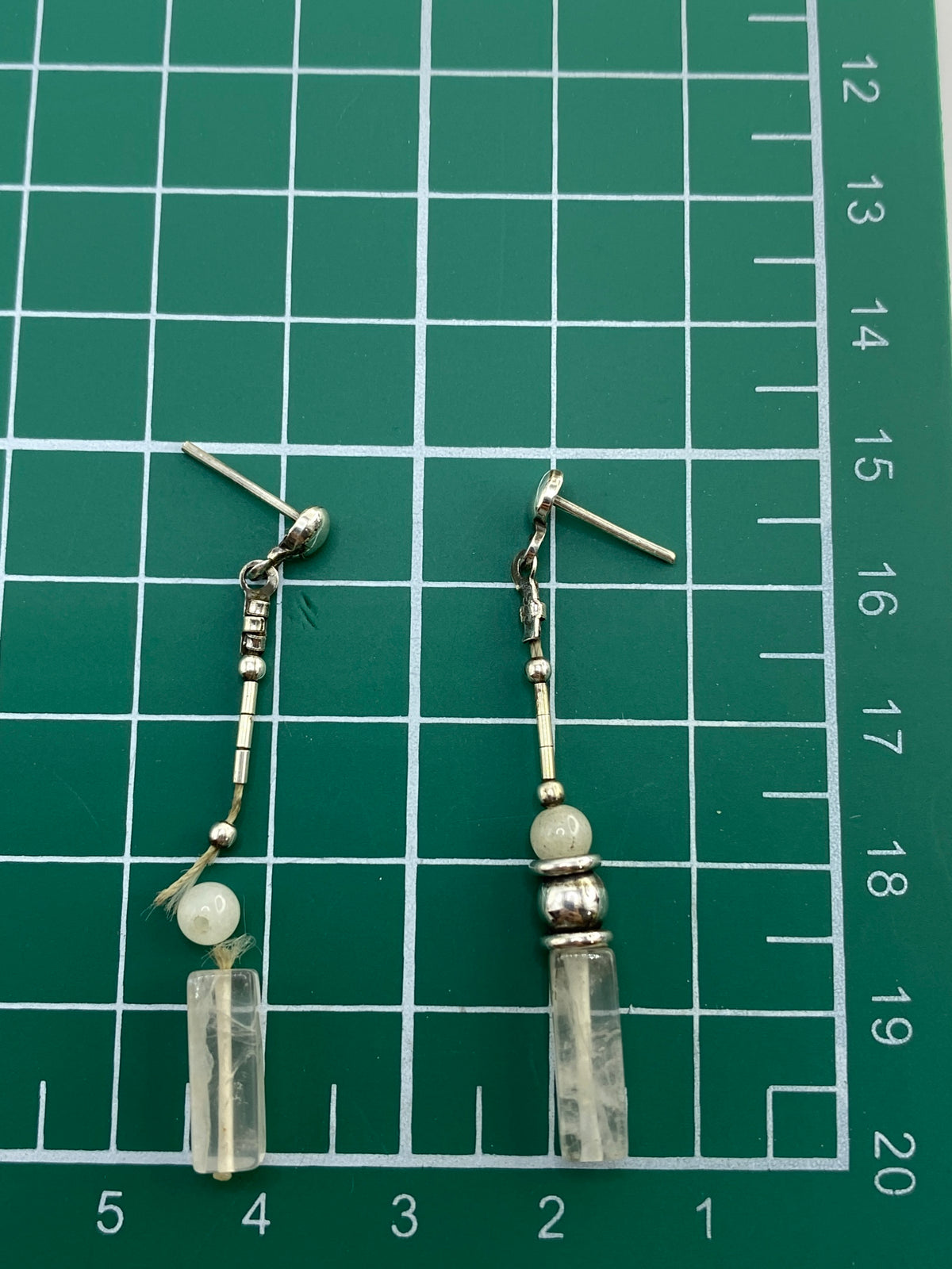 Medida en escala de los aretes: cuarzo blanco de tamaño moderado en postes de plata