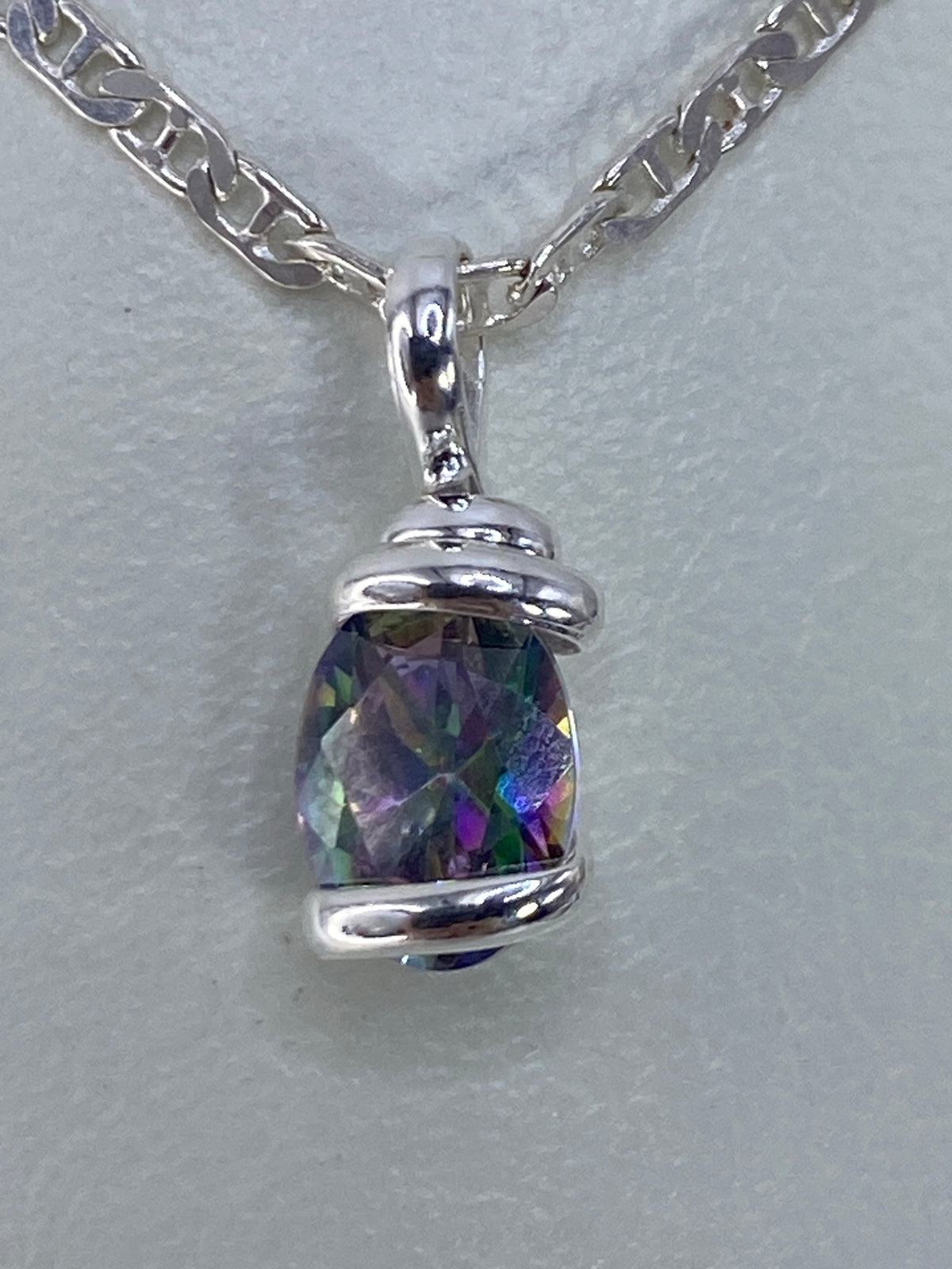 Circonia multicolor refractando luz azul, verde y púrpura en el dije