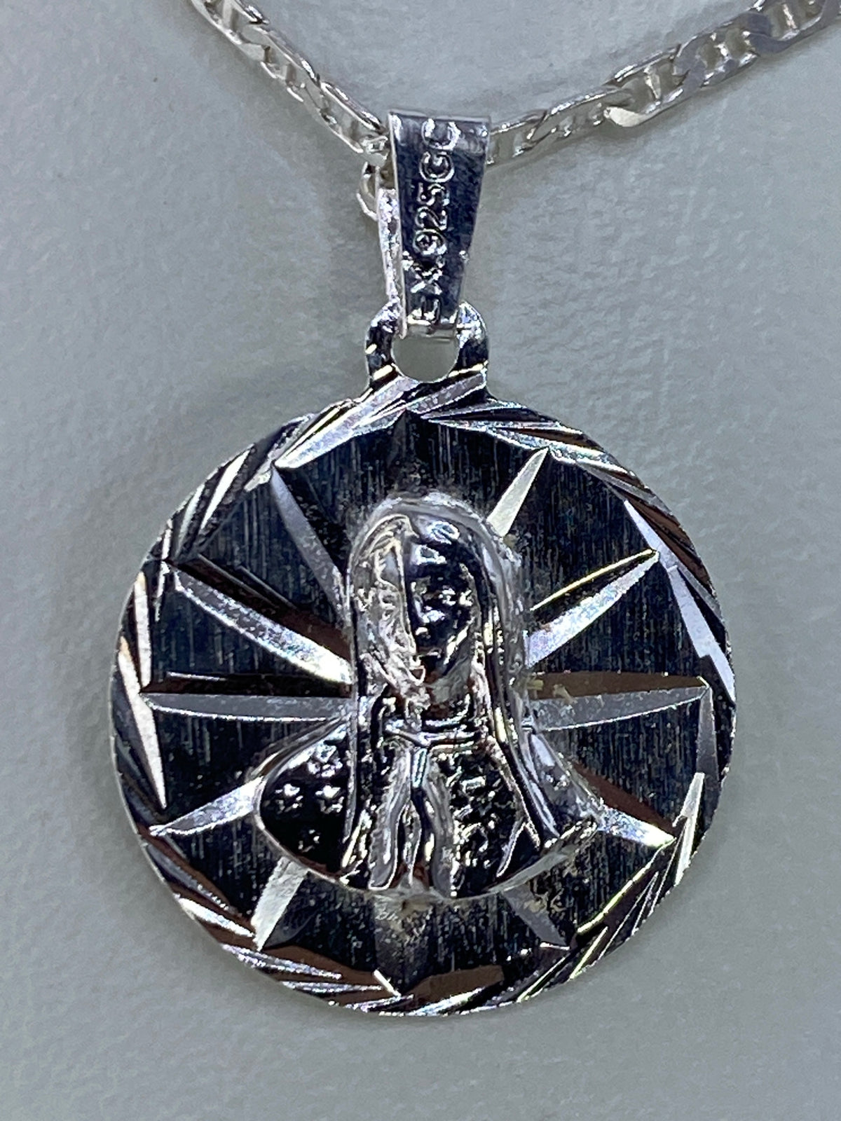 Dije de plata con Virgen María repujada y rayos radiales de luz