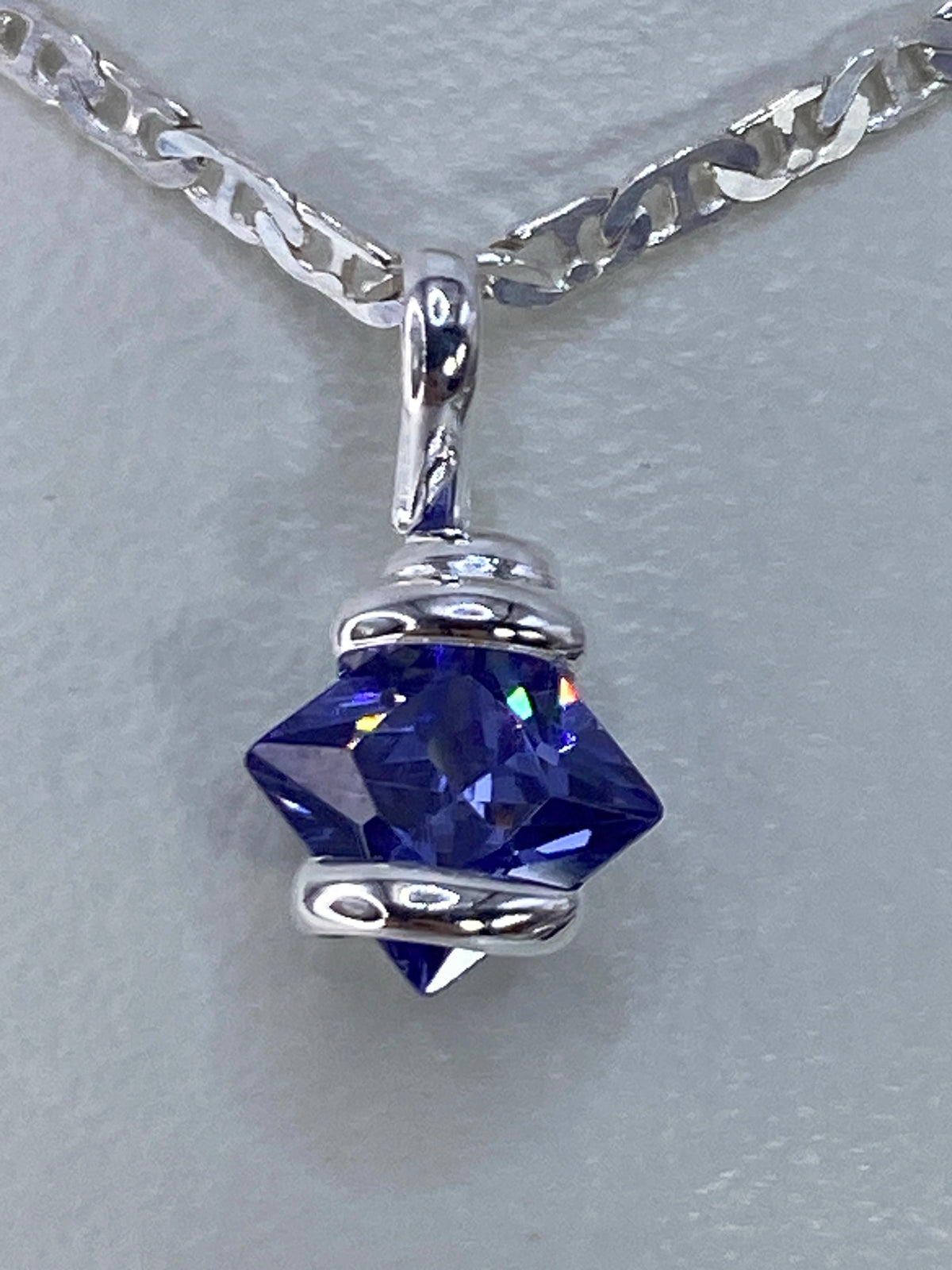 Dije de plata 925 con circonia azul engastada, visto de frente colgado de una cadena