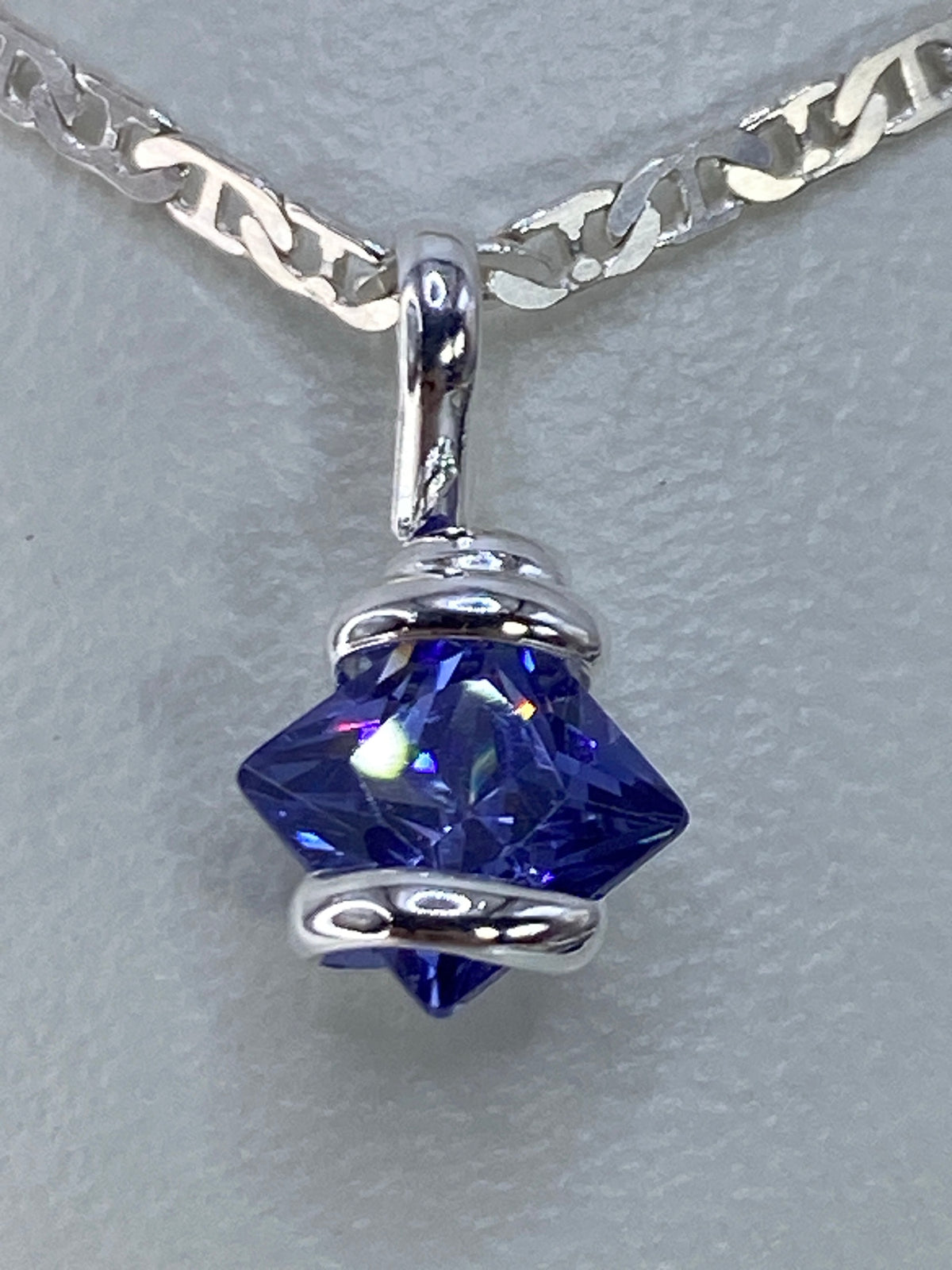 Detalle del dije mostrando el engaste de circonia azul y el pulido de plata 925