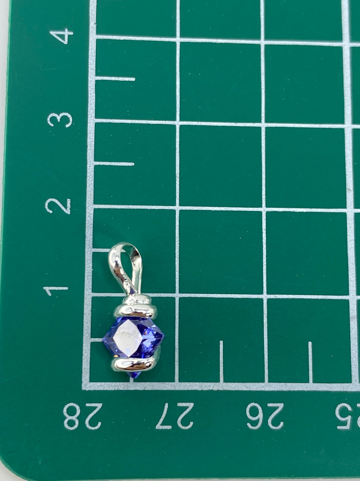 Dije de plata con circonia azul desde ángulo lateral en fondo blanco