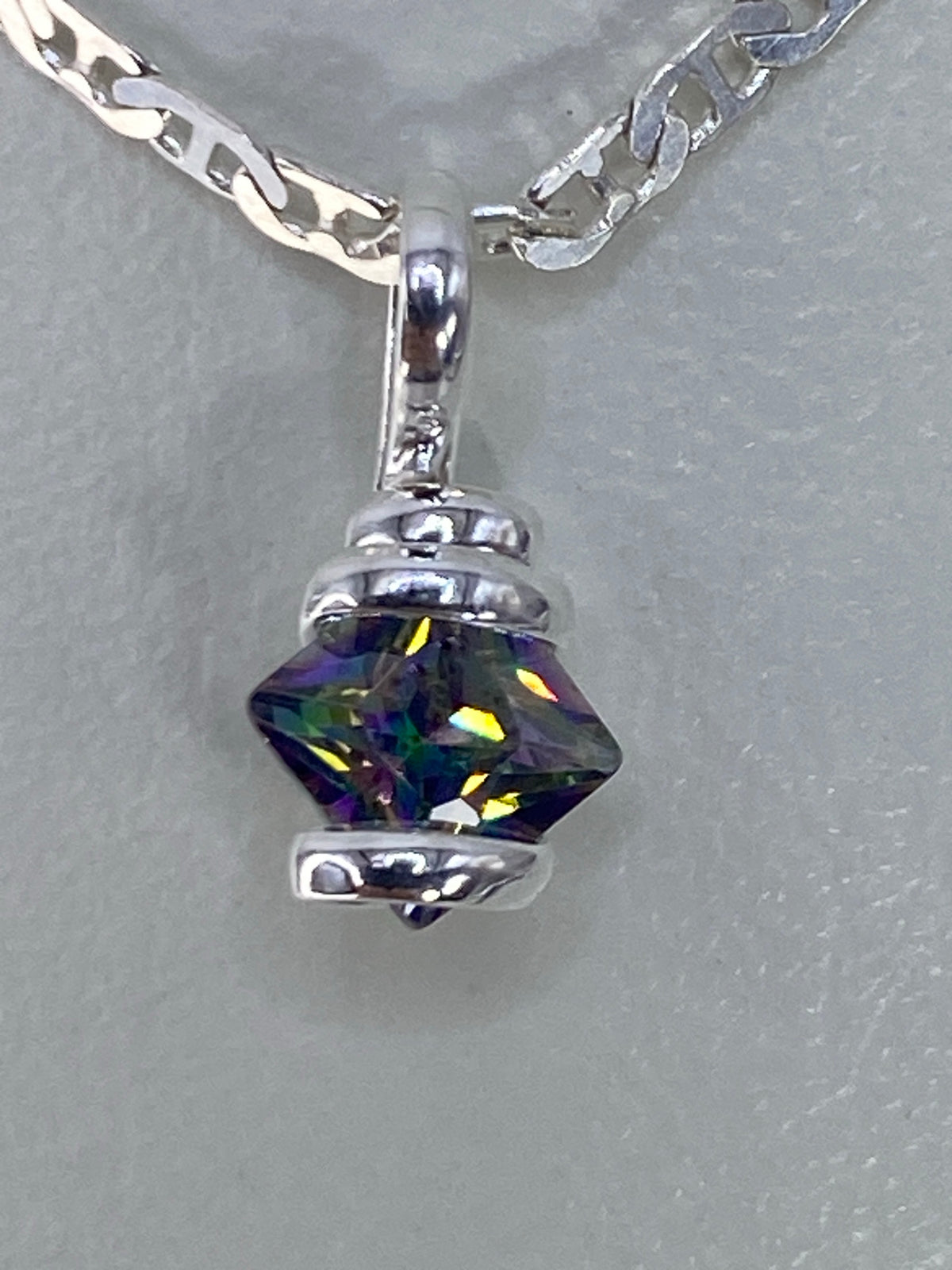 Detalle del dije de 1.3 cm mostrando los reflejos azules, verdes y amarillos de la circonia