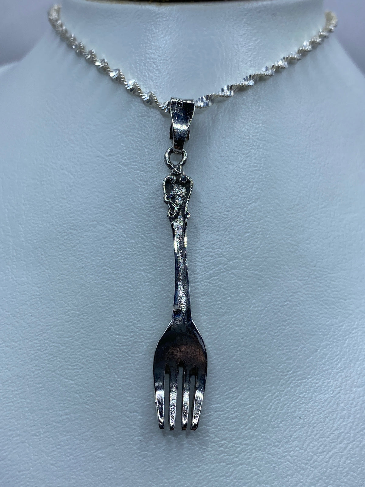 Detalle del dije de tenedor en plata pulida — cinco centímetros de largo