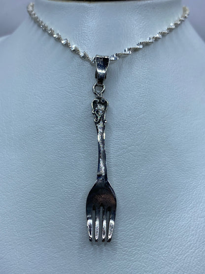 Detalle del dije de tenedor en plata pulida — cinco centímetros de largo