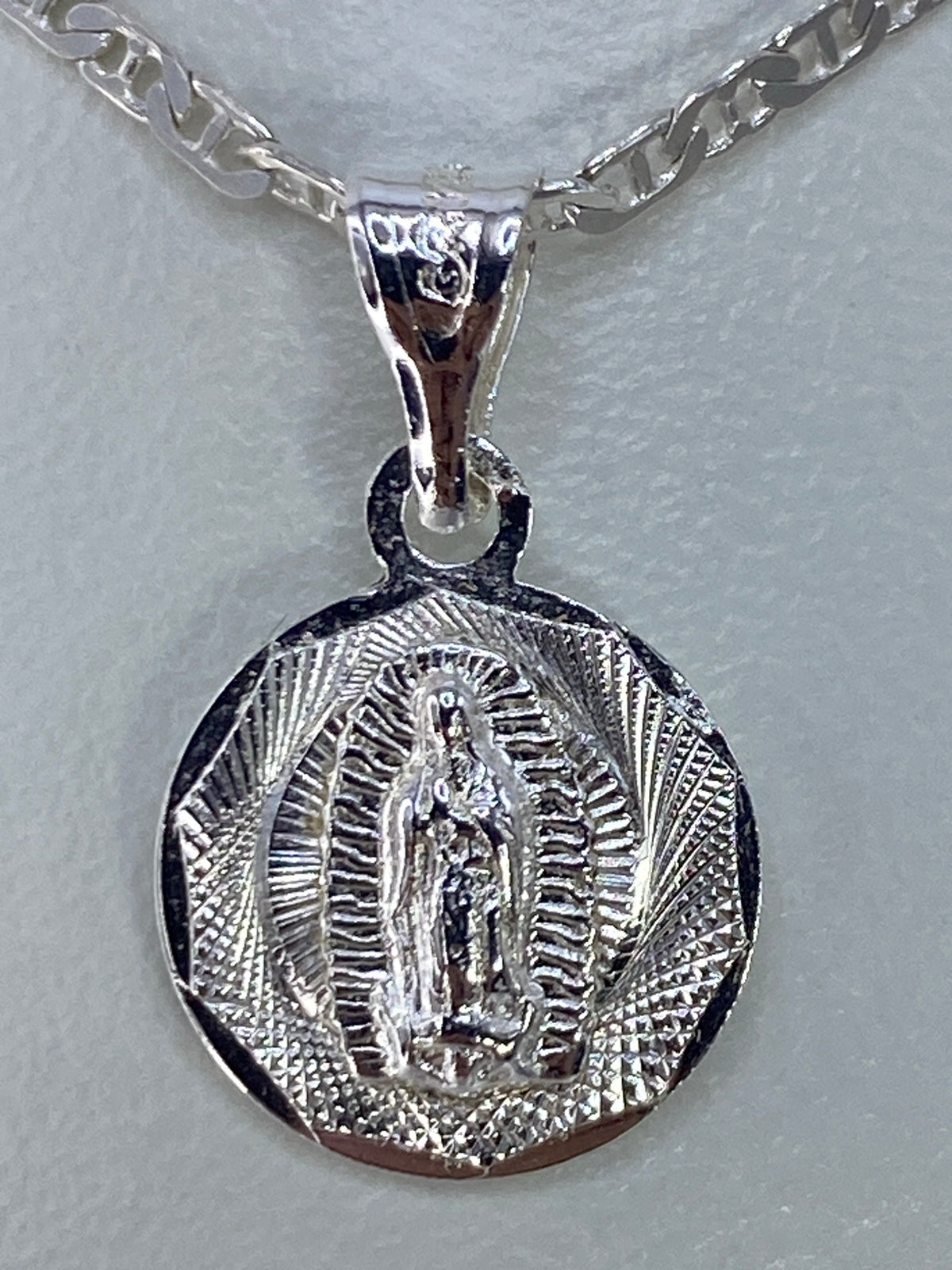 Dije Virgen de Guadalupe en plata 925 repujada, vista frontal con rayos de luz