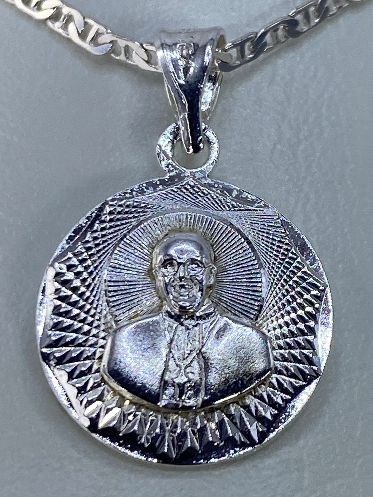 Detalle del repujado de Taxco en el dije religioso de plata 925