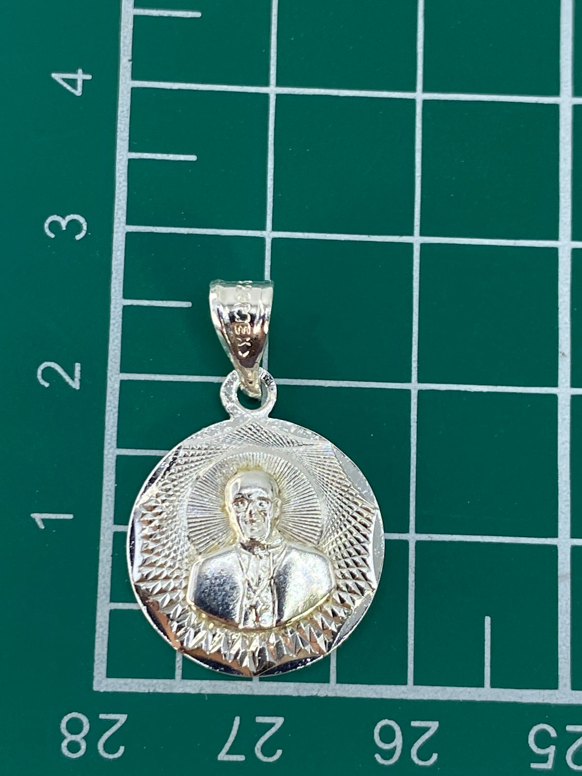 Dije de plata sobre fondo neutro mostrando el acabado pulido