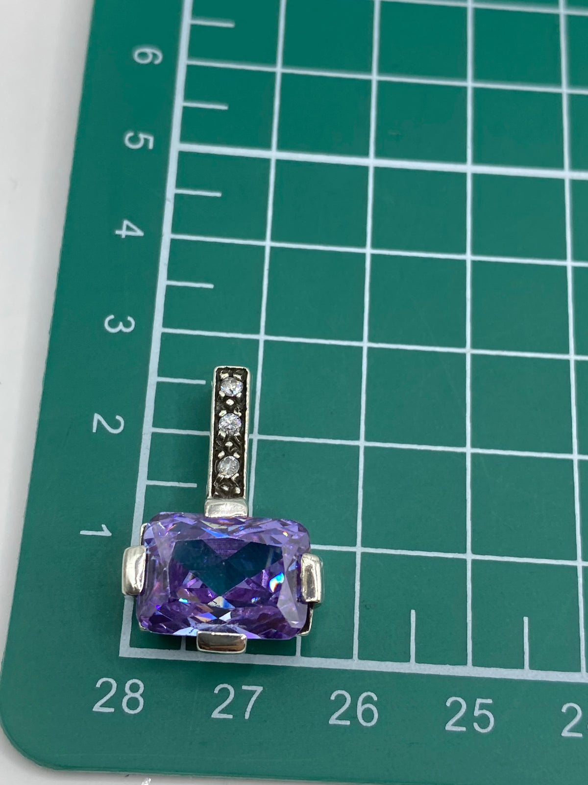Dije sobre regla mostrando su tamaño de 2.4 cm de largo