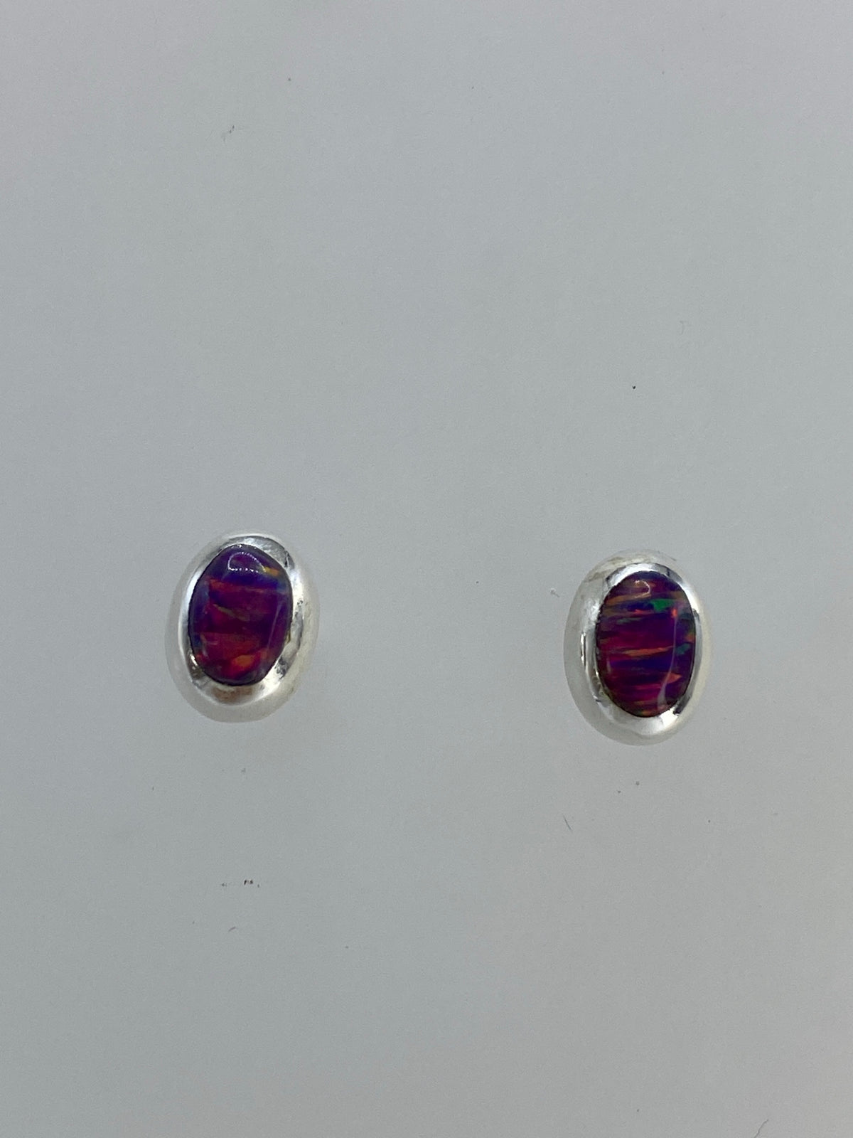Aretes de ópalo de fuego rosa en plata, mostrando el brillo multicolor de la piedra
