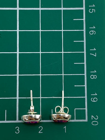 Aretes de plata con ópalo rosa sobre fondo blanco con escala de medida