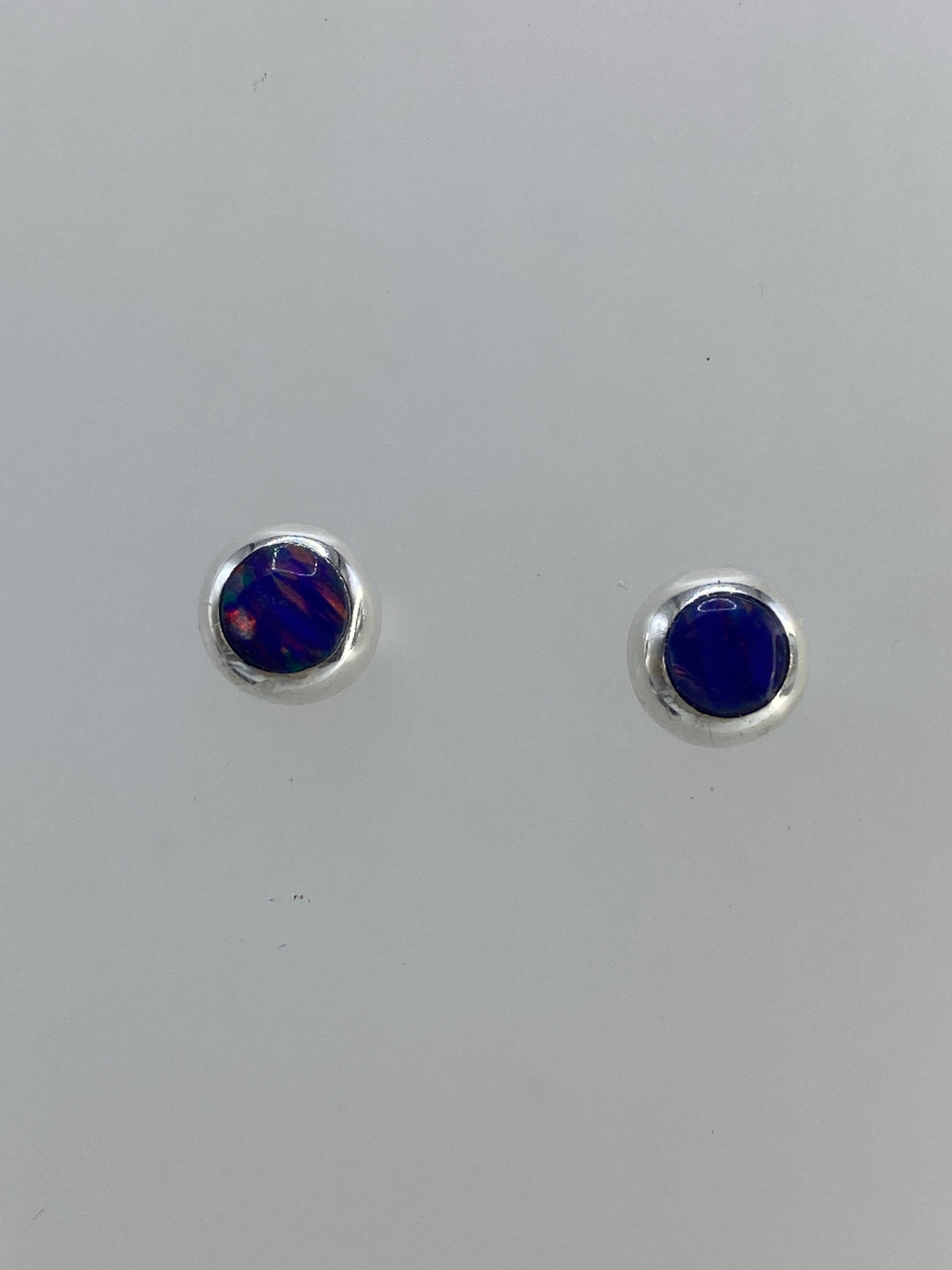 Vista frontal de los aretes de ópalo azul con engaste plateado