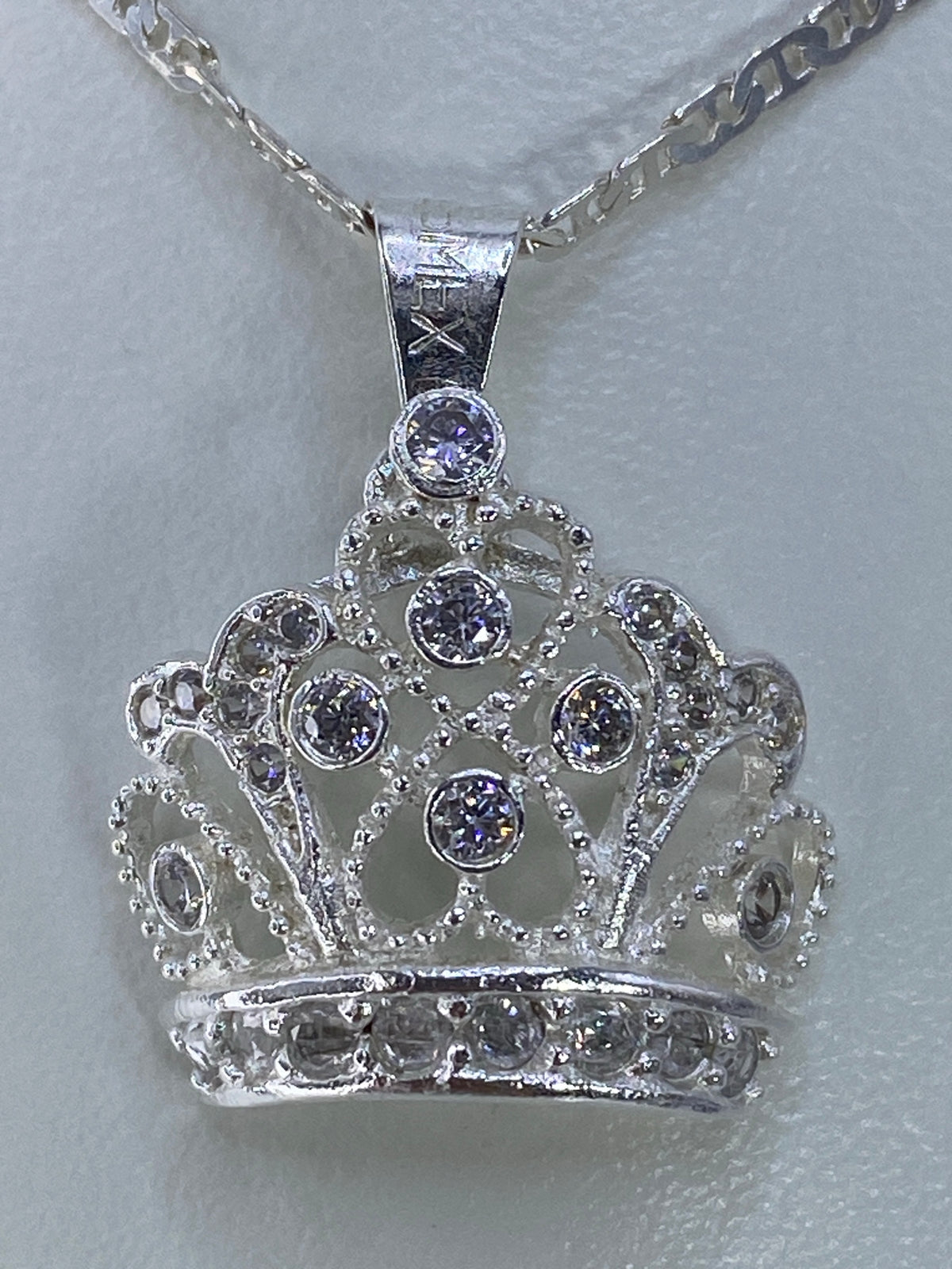 Dije corona de plata 925 con circonia cristalina engastada, colgando de cadena plateada
