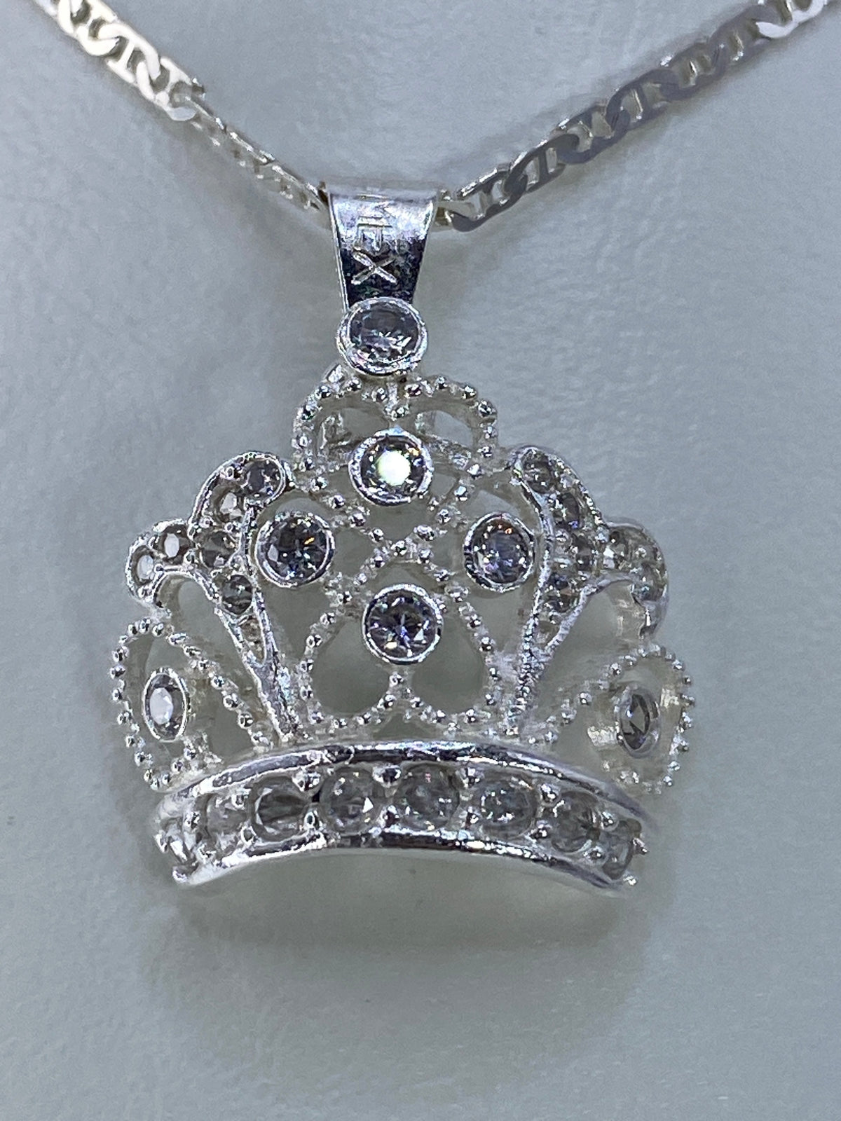 Detalle frontal del dije mostrando las circonias brillantes en patrón corona