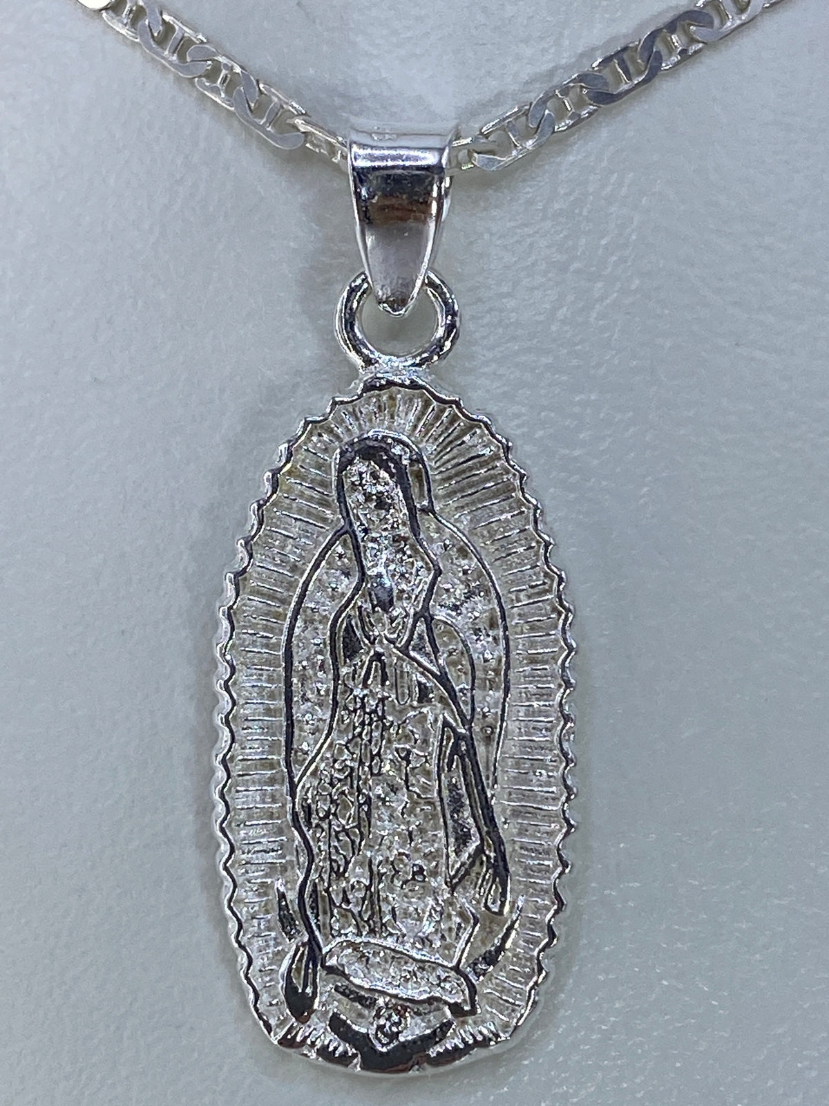 Dije de plata 925 con imagen de la Virgen de Guadalupe repujada a mano, colgado de una cadena plateada