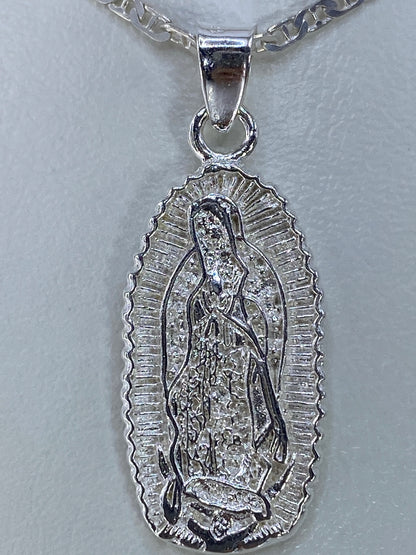 Dije de la Virgen de Guadalupe sobre papel métrico mostrando su tamaño de 3.5 cm