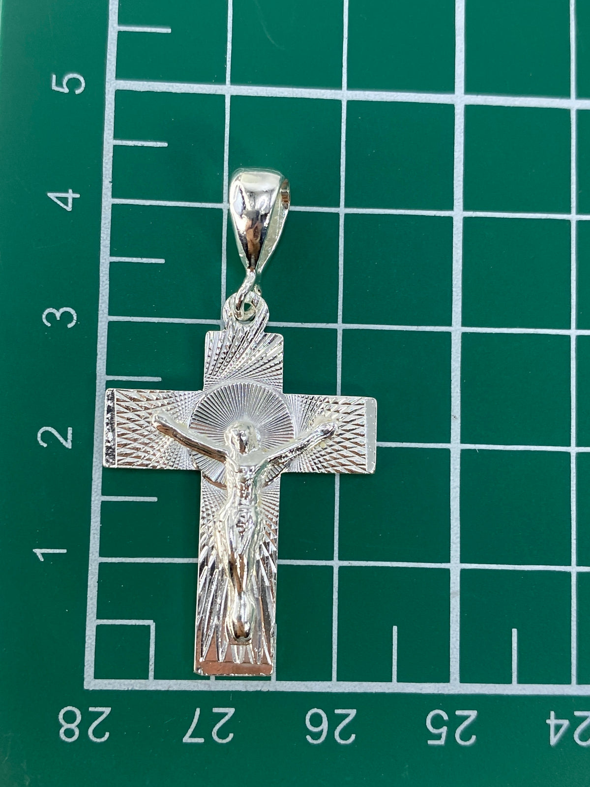 Reverso del dije cruz mostrando el trabajo de repujado y acabado brillante