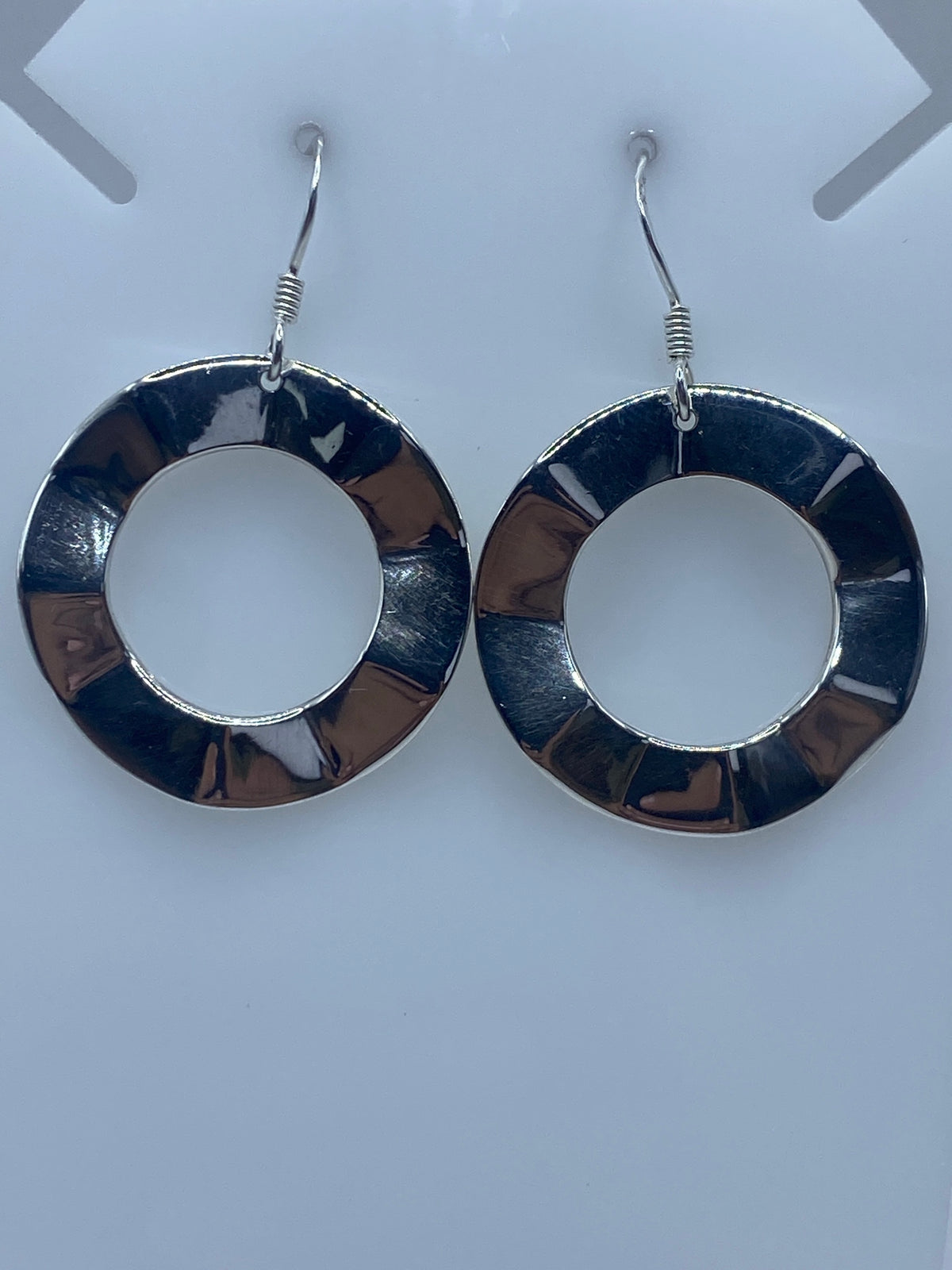 Par de aretes de plata con segmentos repujados, vistos de frente sobre fondo blanco