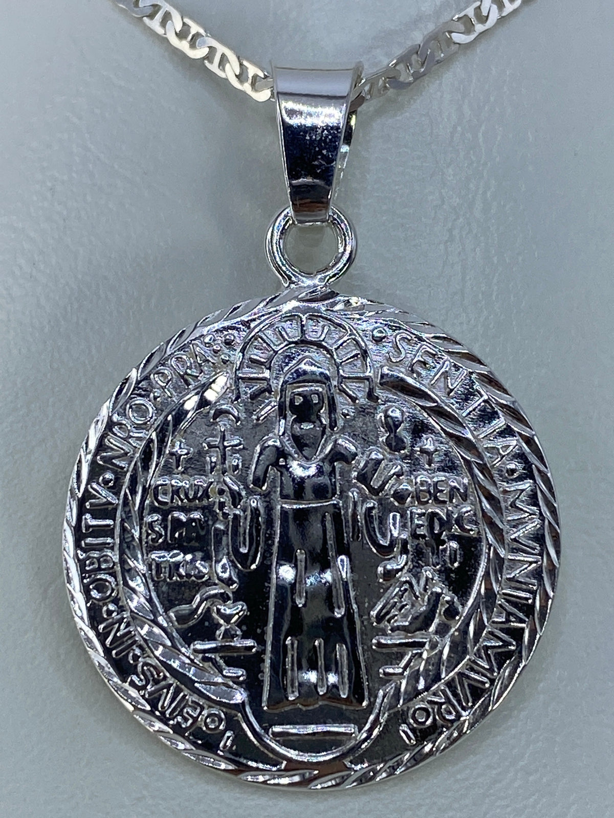 Dije San Benito repujado en plata 925 de Taxco, frente con figura de santo y cruz central