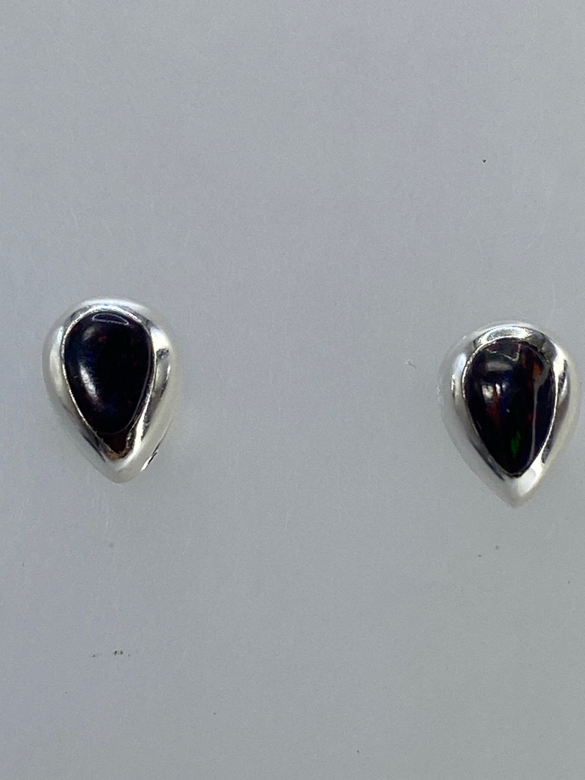 Aretes sobre fondo gris mostrando el pulido de la plata 925 y el Quinto