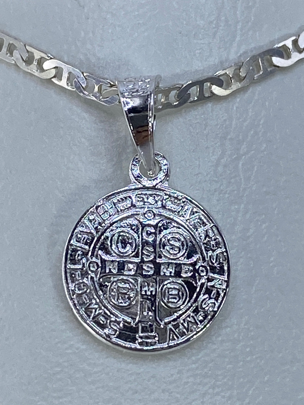 Dije Medalla de San Benito en plata 925 repujada, frente y reverso visibles en cadena plateada