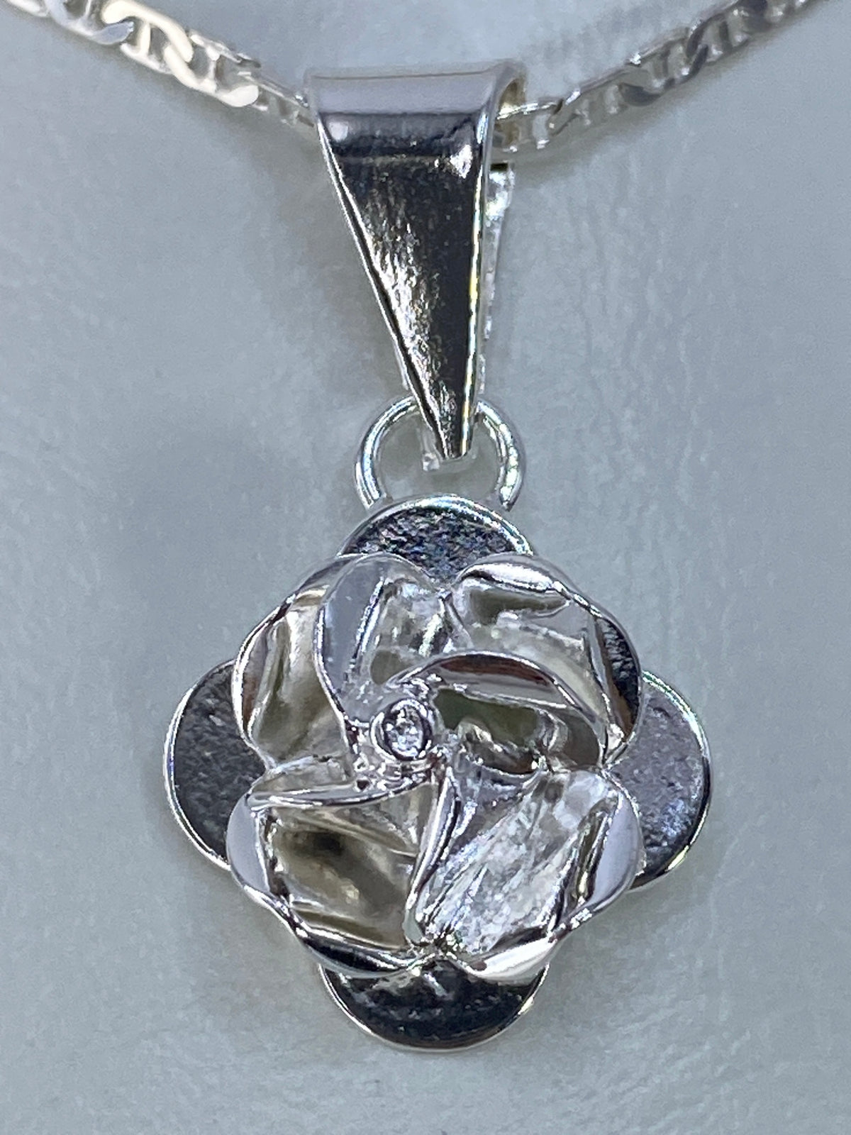 Dije floral de plata repujada de 3 cm colgando de una cadena plateada