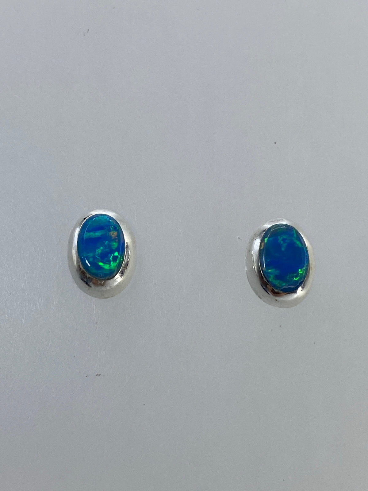Detalle del engaste a mano del ópalo en plata 925, mostrando los colores verdes y azules
