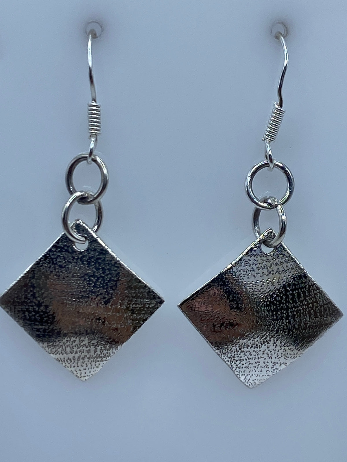 Par de aretes de plata 925 con repujado geométrico, cuadrado bicolor, sobre fondo gris