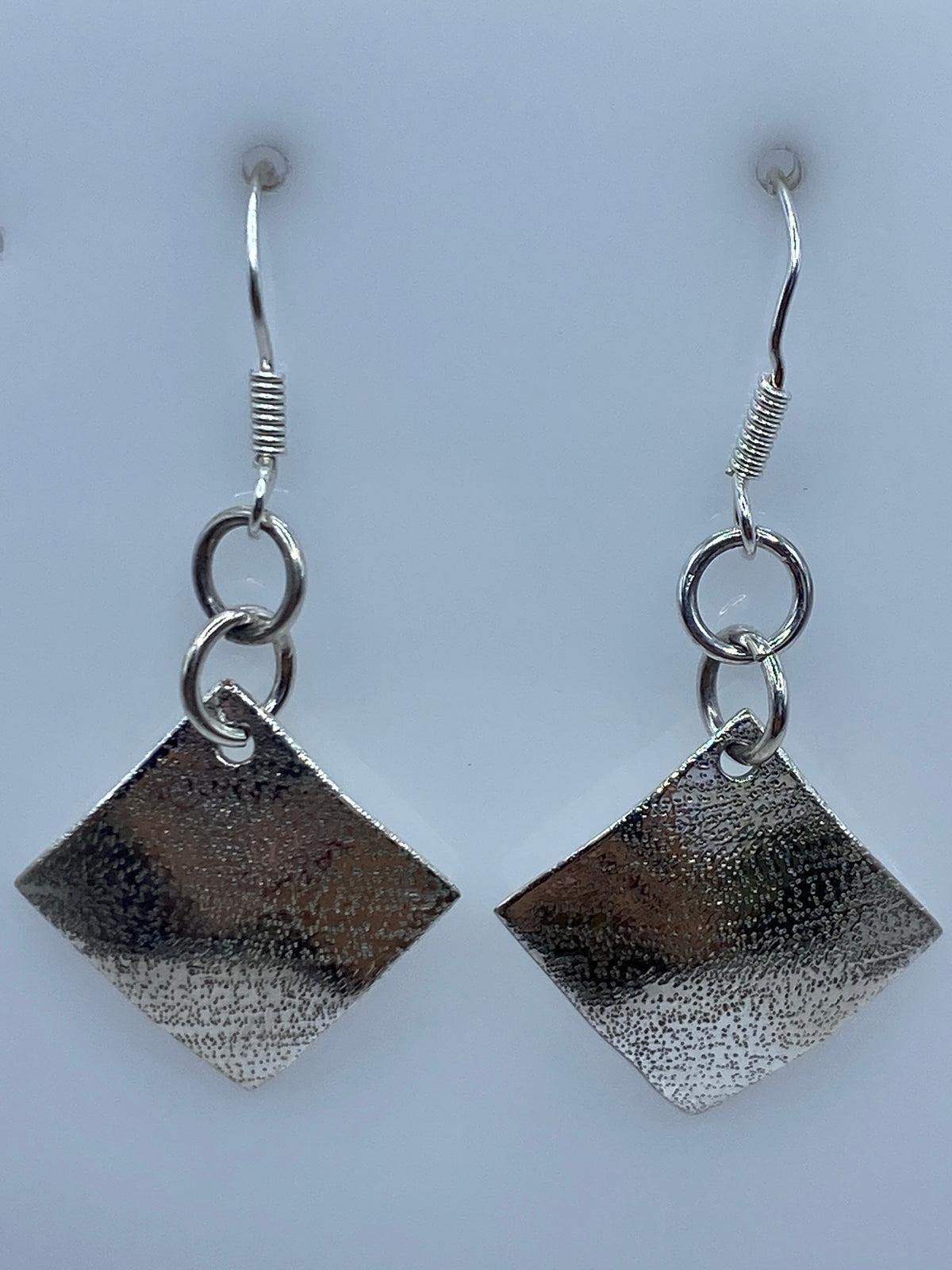 Aretes de plata repujada sobre regla: largo 4.3 cm, mostrando escala real