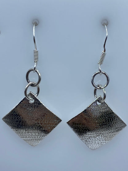 Aretes de plata repujada sobre regla: largo 4.3 cm, mostrando escala real