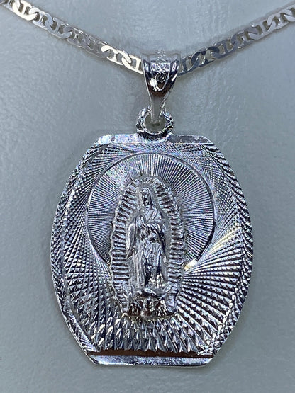 Dije de plata repujado con Virgen de Guadalupe y halo radiante, colgado de cadena de eslabones