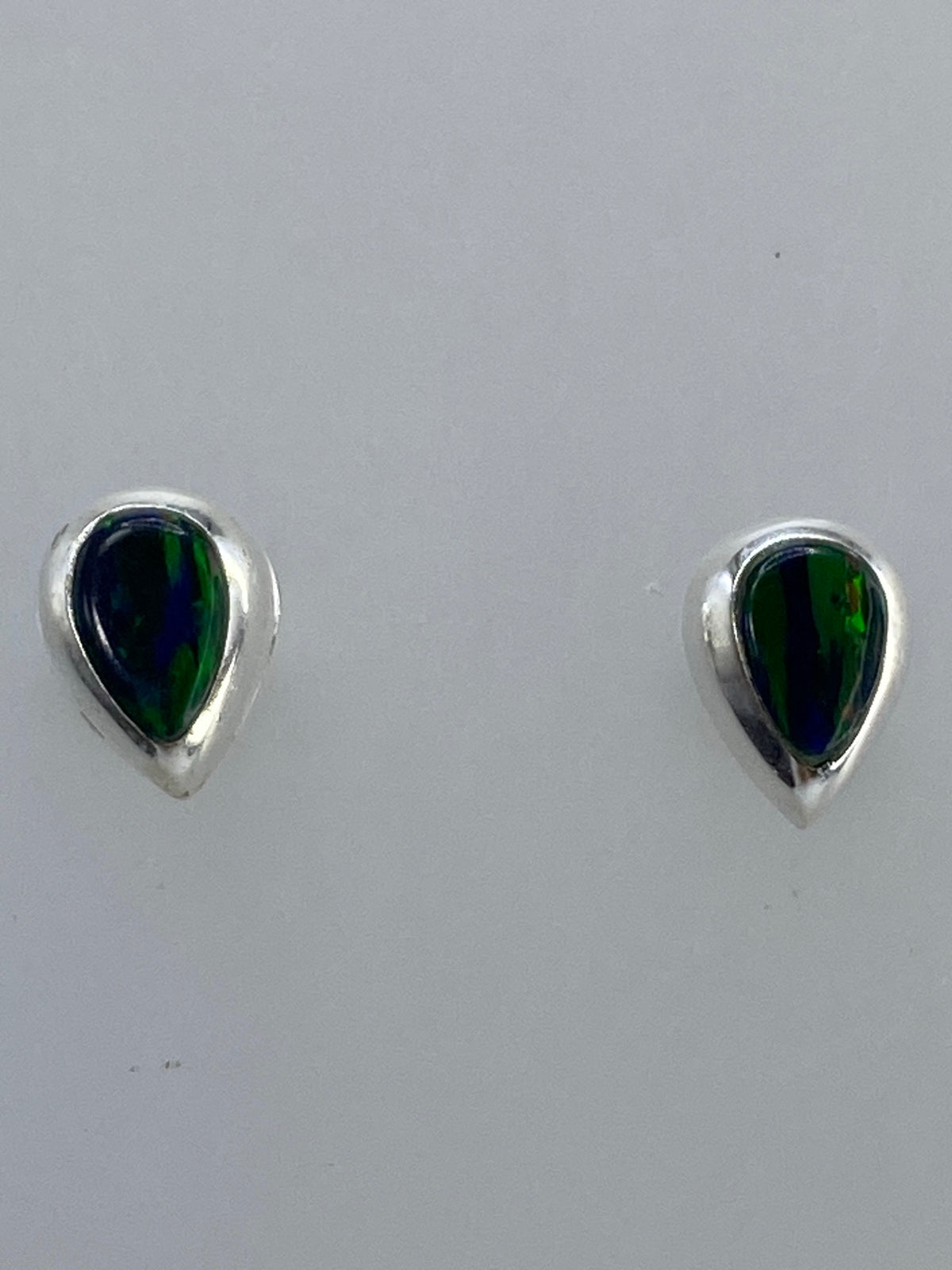 Par de aretes de plata con ópalo de fuego multicolor, mostrando los tonos rojo, naranja, verde y azul