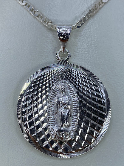 Primer plano del rostro de la Virgen de Guadalupe en el dije, mostrando el detalle del repujado a mano