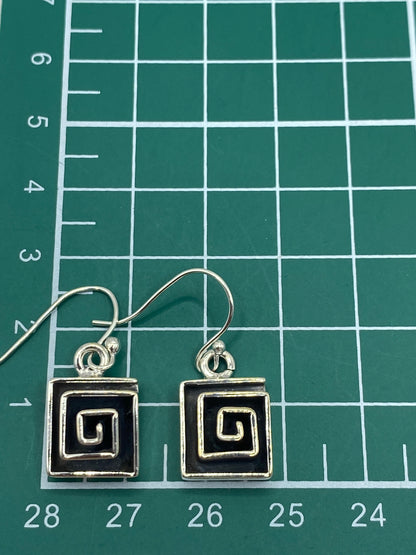 Aretes de espiral griega en plata 925 sobre fondo blanco mostrando el Quinto