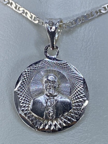 Dije de plata repujado con motivo espiritual y halo de rayos, de frente