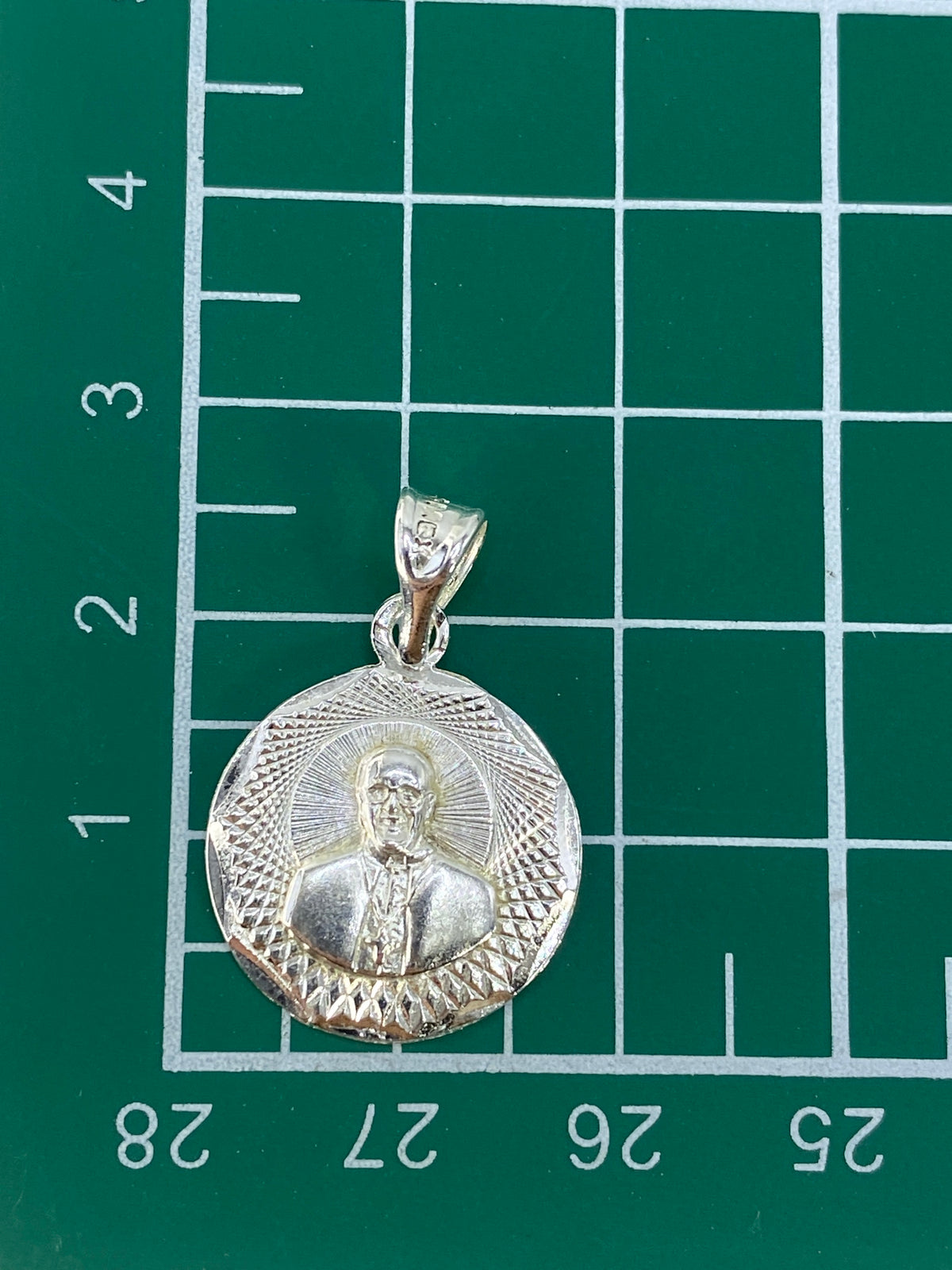 Dije de 2.5 cm sobre escala de medida mostrando tamaño real