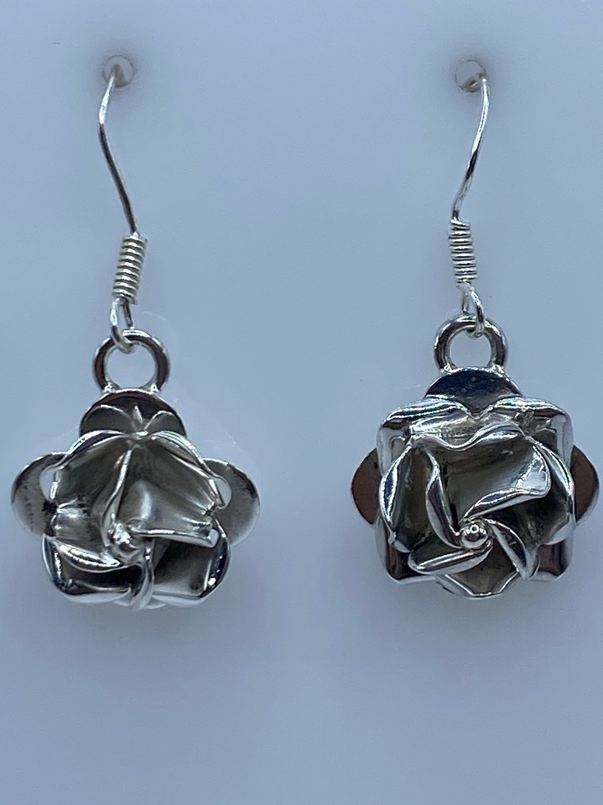 Par de aretes de plata 925 en forma de flor con repujado artesanal, colgando de ganchos de plata